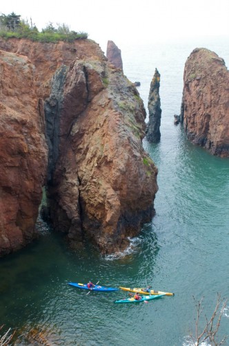 Kayakers explore the 'Three Sisters' rock formations that rise from the waters off the Bay of Fundy at Eatonville in Cape Chignecto Provincial Park - Credit Photo Nova Scotia Tourism